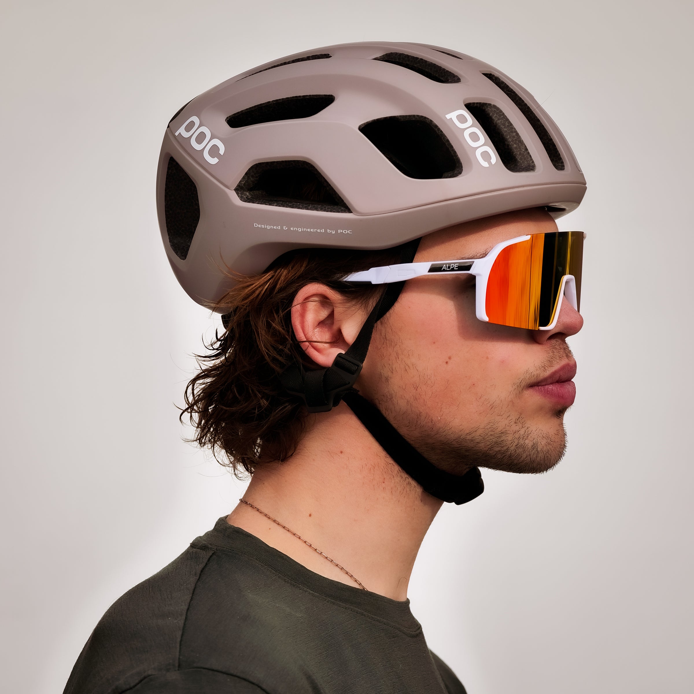 Person wearing a bike helmet and sunglasses from ALPE Eyewear on a plain background
